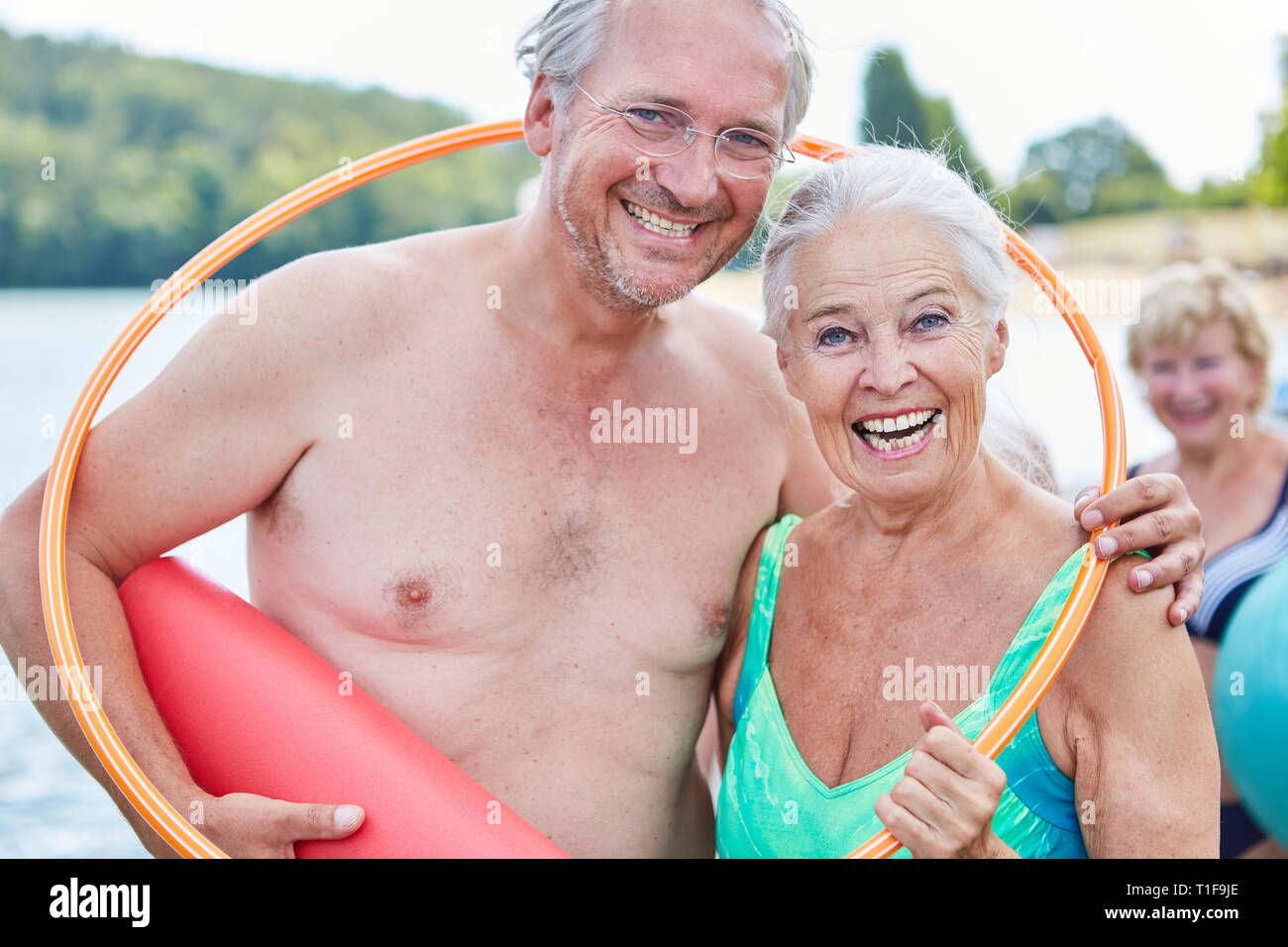 Lachend vital senior Paar im Sommer Urlaub mit einem Reifen und Yoga Matte Stockfoto