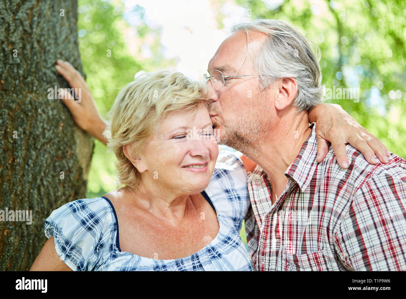 In liebe Senior gibt seiner Freundin einen Kuss in der Natur im Sommer in dating Stockfoto