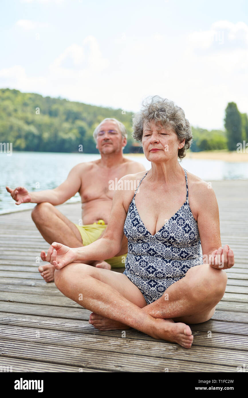 Zwei seniors eine Yoga Übung in einem Wellness Workshop auf dem See im Sommer Stockfoto