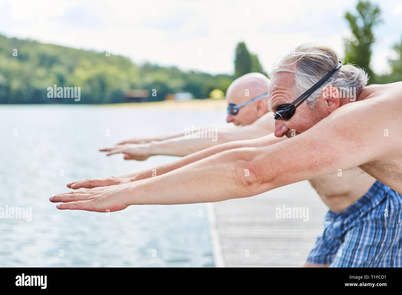 Zwei wichtige ältere Männer auf dem Steg am See am Anfang vor dem Sprung ins Wasser. Stockfoto