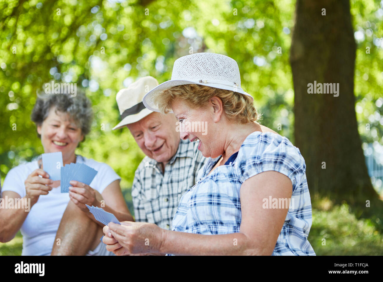 Happy Senioren Spielkarten im Sommer im Garten des Seniorenheims Stockfoto