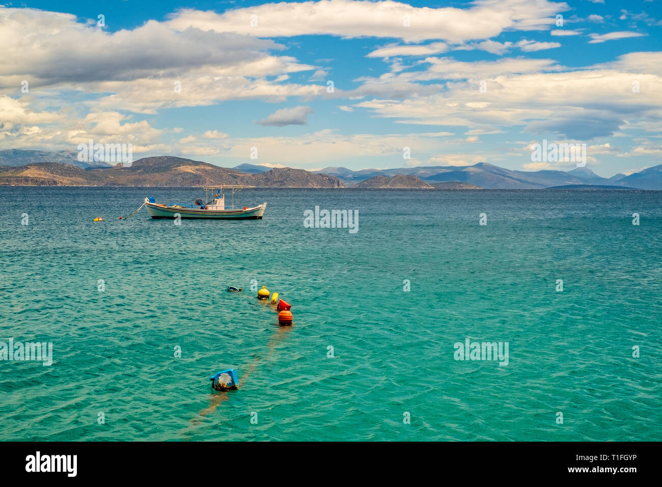 Holz- Boot schwimmend in einem schönen klaren smaragdgrünen Wasser. Peloponnes, Griechenland. Stockfoto