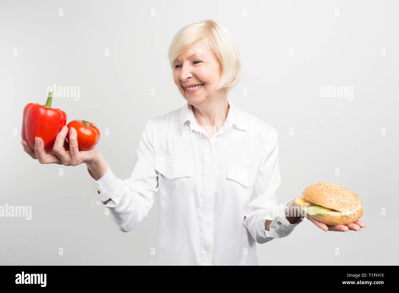 Ein Bild von Dilemma zwischen gut und schlecht gegessen. Was ist besser: Zwei gute Paprika oder einen leckeren Burger. Die Antwort liegt auf der Hand, aber nicht einfach zu Stockfoto