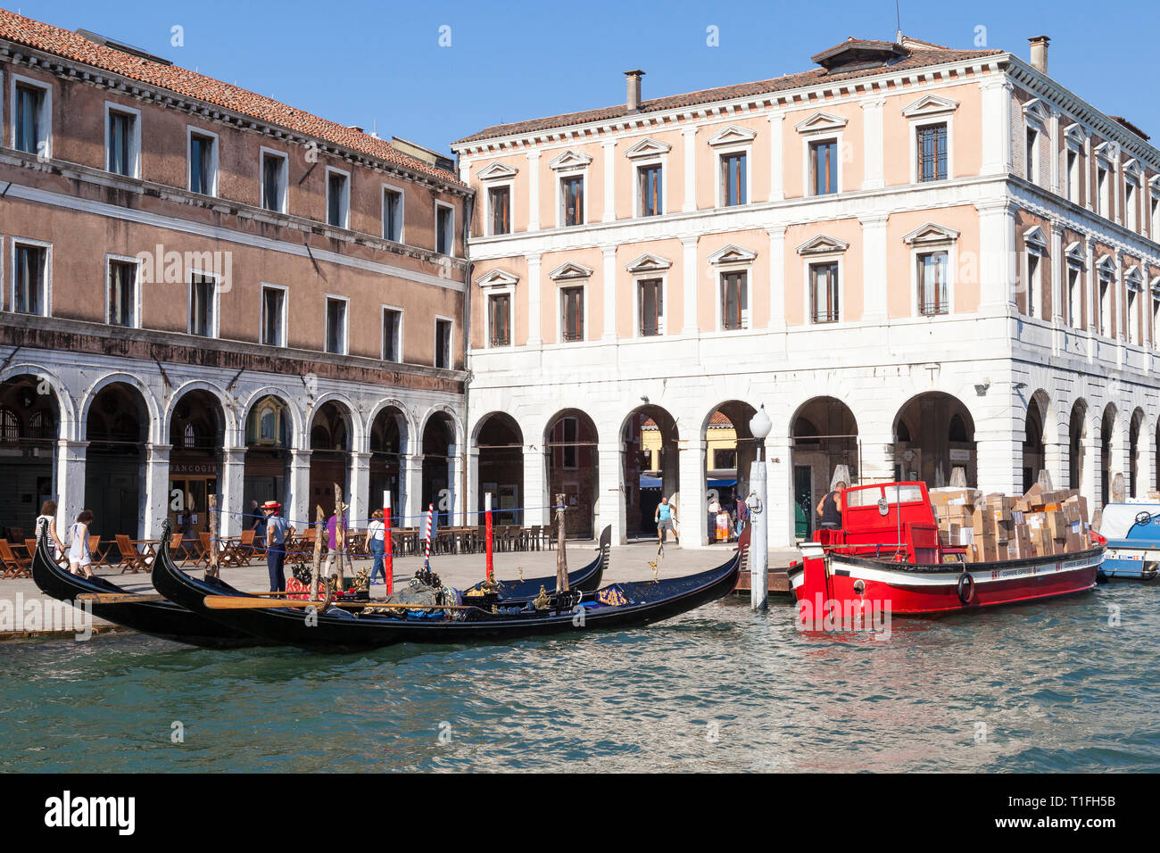 Gondeln und bunte rote Arbeit Boot die Auslieferung von Paketen in Campo Erberia, Grand Canal, San Polo, Venedig, Venetien, Italien Stockfoto