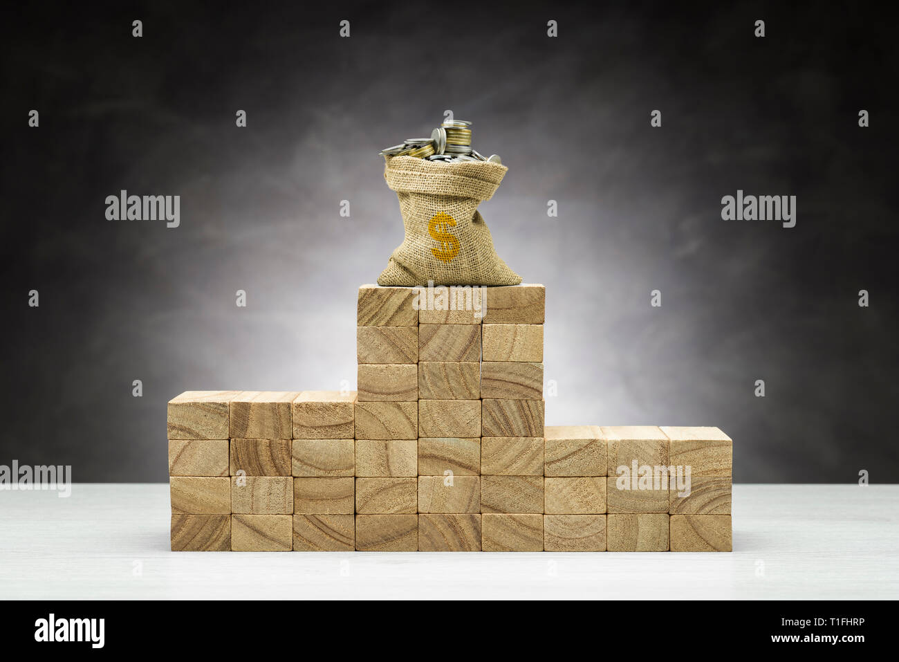 Konzept des Wettbewerbs. Holz- Podium auf grauem Hintergrund mit Beutel voller Münzen. Stockfoto