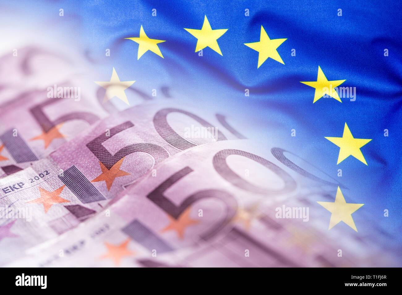 Bunte wehende Fahne der Europäischen Union auf einen Euro Geld Hintergrund Stockfoto