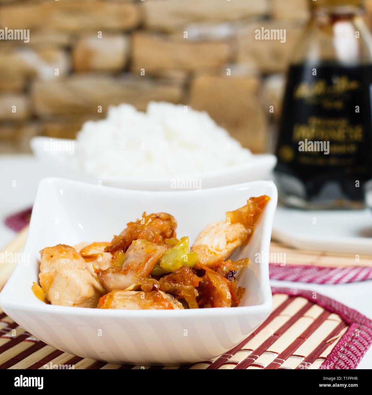 Mit der asiatischen Huhn mit Schüssel Reis und dunkle Sojasauce auf Bambus Matte Stockfoto