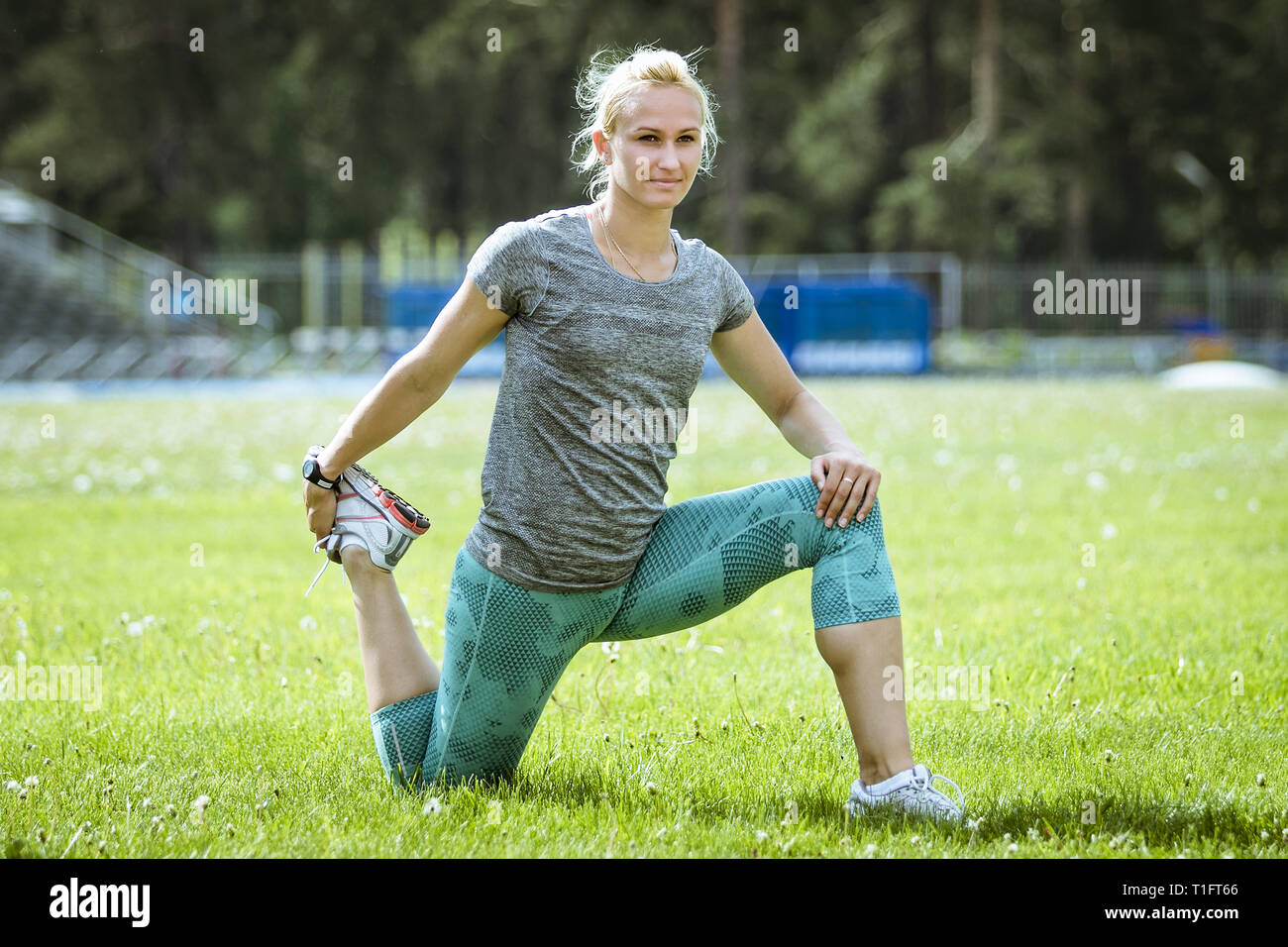 Weibliche Training stretching Beine im grünen Gras Feld Stockfoto