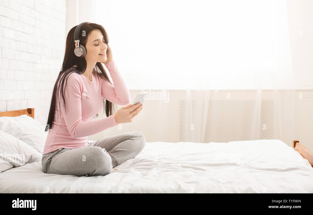 Junge schöne Frau entspannen und Musik hören im Bett Stockfoto