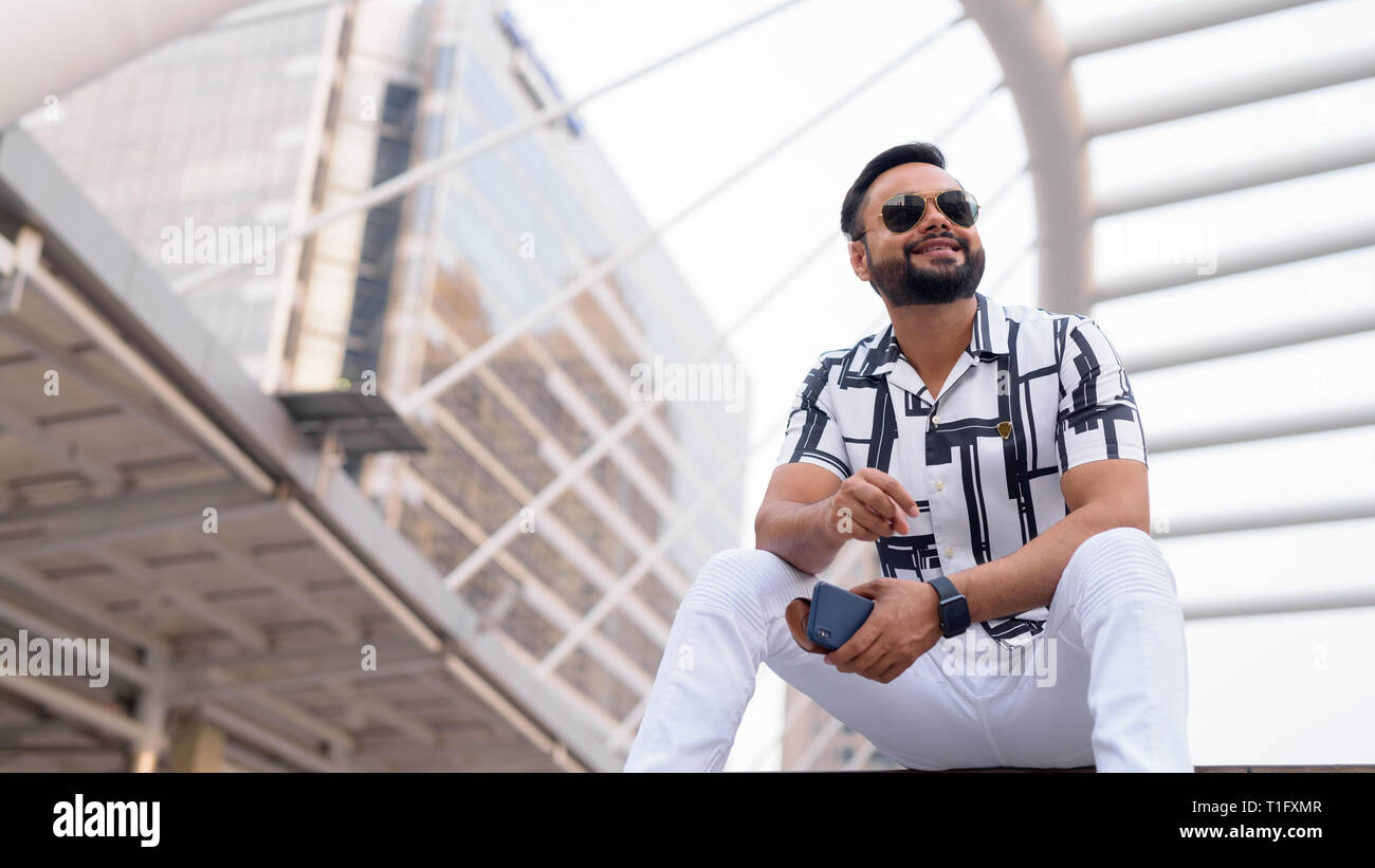 Junge Bartgeier indischen Mann mit Sonnenbrille sitzen in der Stadt draußen Stockfoto