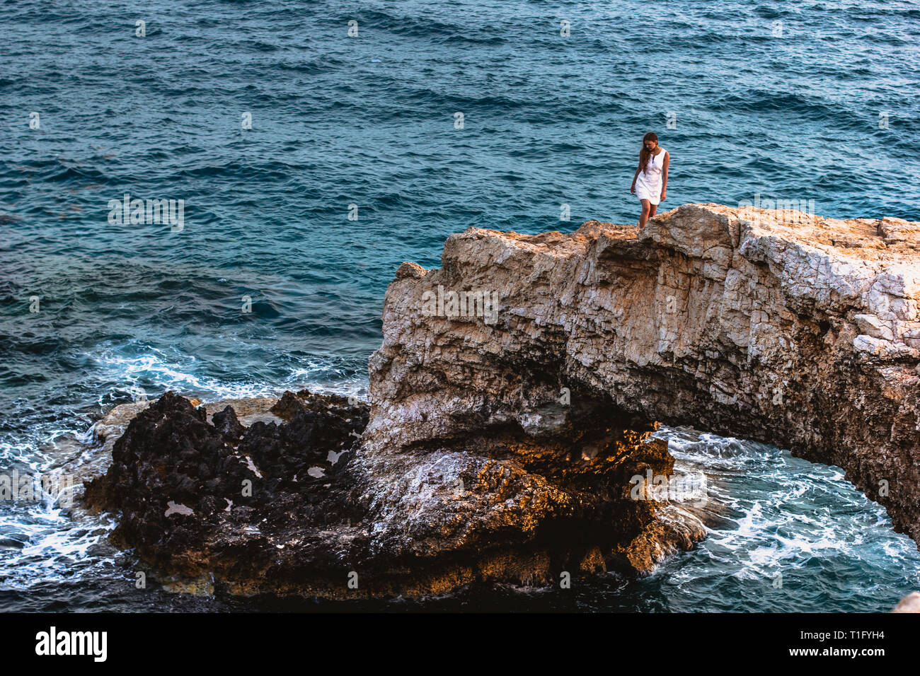Frau in weißem Kleid auf der schönen natürlichen Felsbogen in der Nähe von Ayia Napa Cavo Greco und Protaras auf Zypern Insel, Mittelmeer. Legendäre Stockfoto