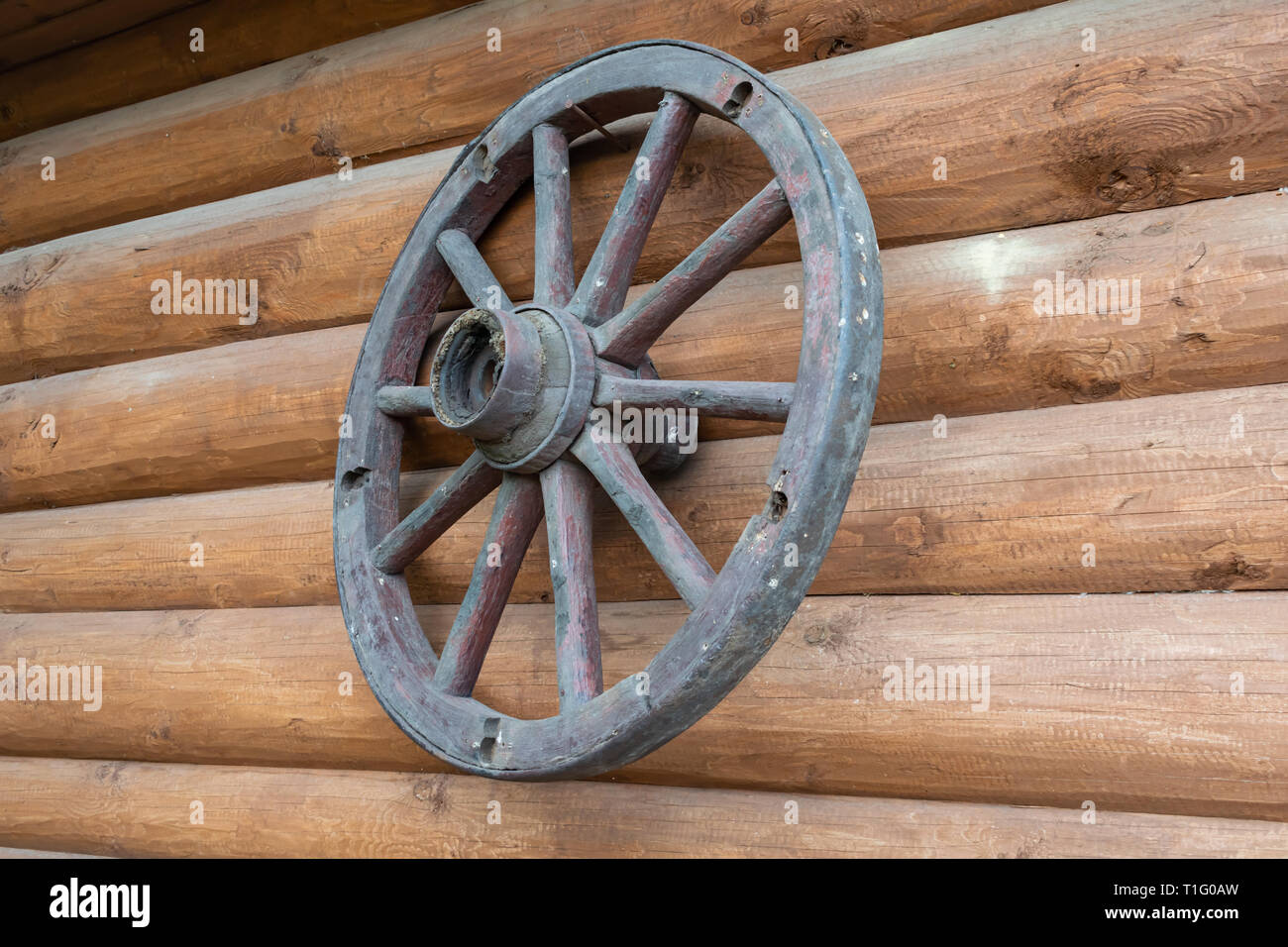 Die alte Wagenrad hängt an der Wand eines Log House als Talisman Stockfoto