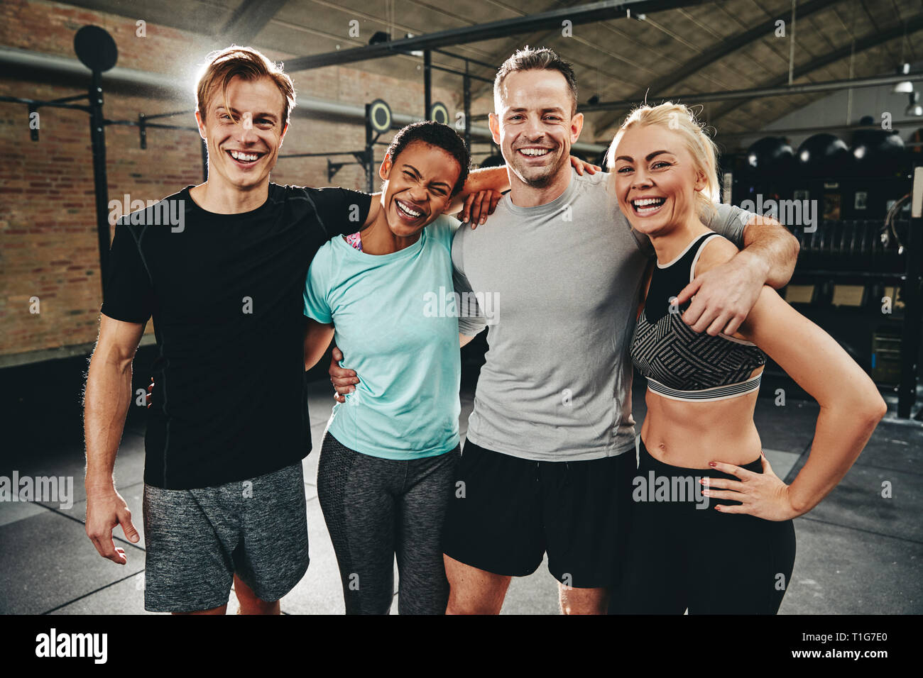 Lachend Gruppe von diversen Freunden in Sportkleidung ständigen Arm in Arm nach dem arbeiten zusammen an der Turnhalle Stockfoto