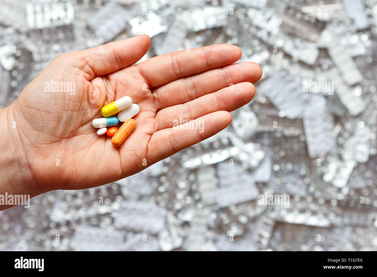 Hand mit vielen verschiedenen Tabletten vor leeren blister Pakete, multi-Medikation Konzept Stockfoto