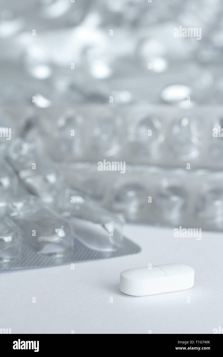 Eine einzige Tablette vor vielen leeren blister Pakete auf weißem Hintergrund, Drogenmissbrauch Konzept Stockfoto