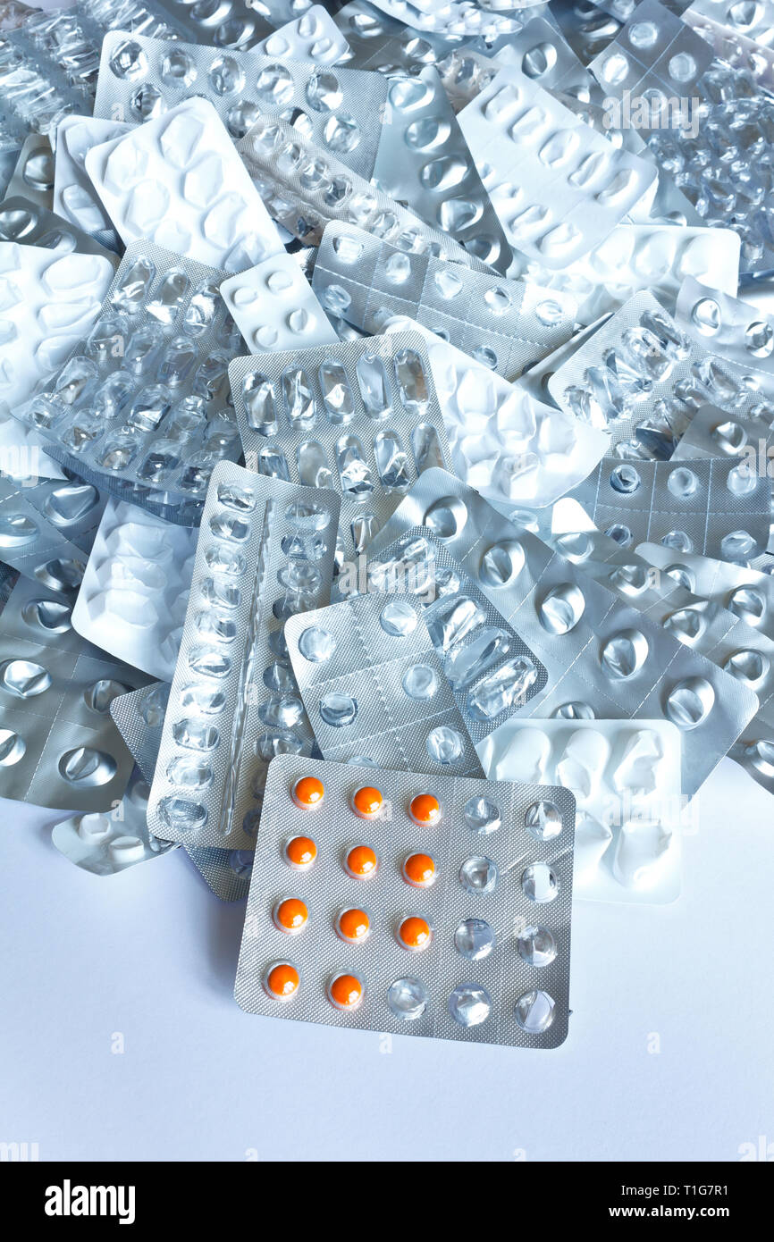 Orange Pillen in Blisterpackung vor vielen leeren Verpackungen, Überdosis Konzept Hintergrund Stockfoto