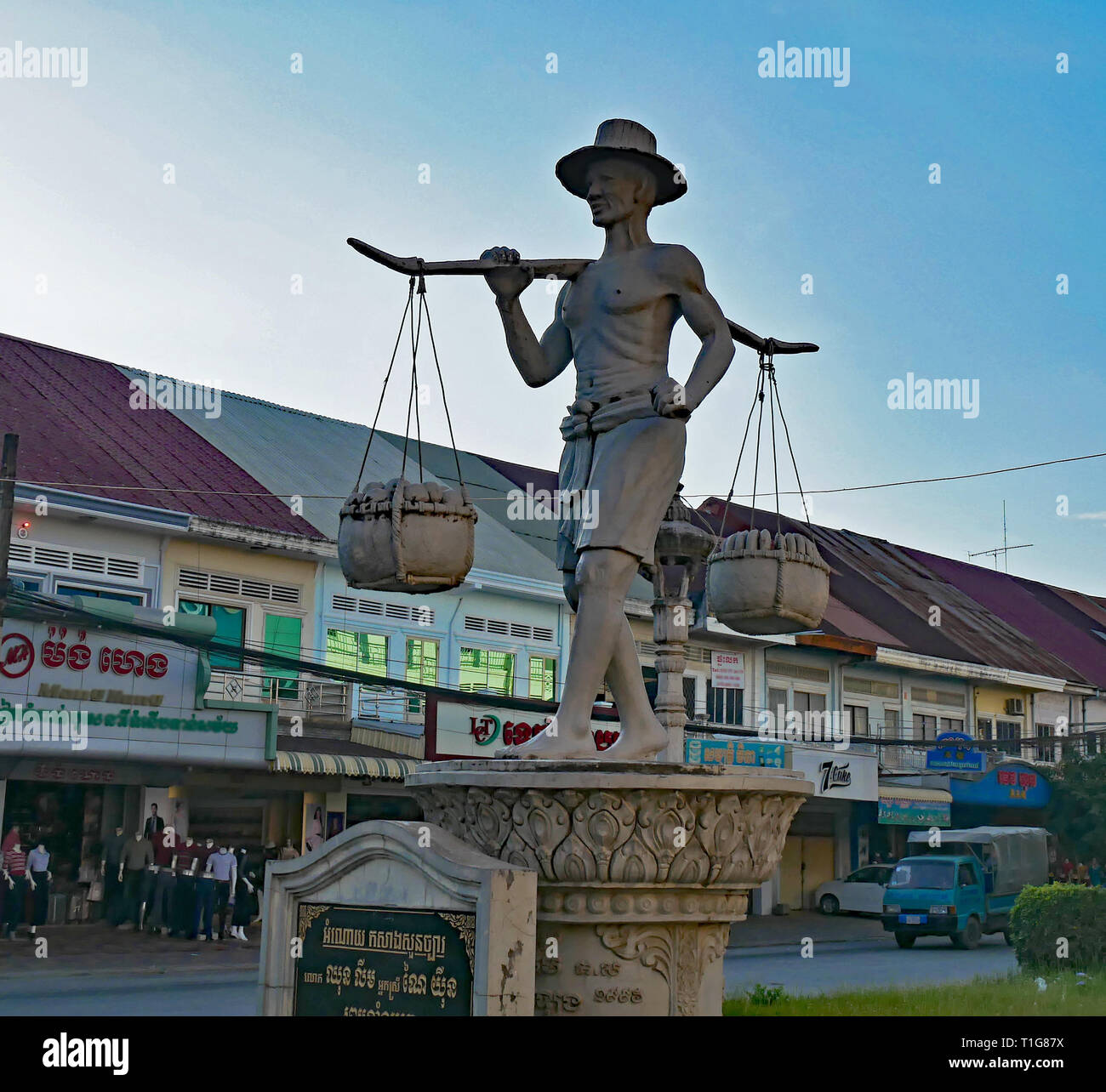 Der Pedlar Statue wird von einem Mann mit einer Gabel über seine Schultern, die Körbe mit Obst zum Verkauf, Handel in Battambang Stadt. Stockfoto