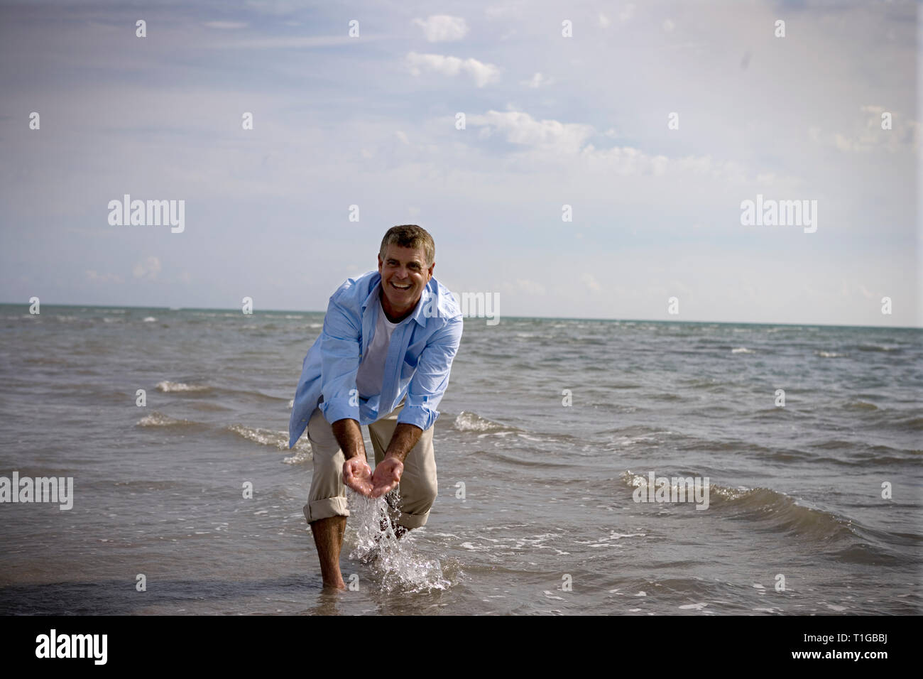 Reifen erwachsenen Mann Spritzwasser auf einem Strand. Stockfoto
