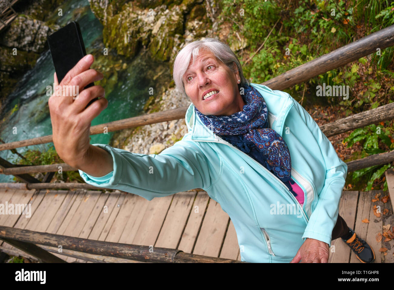 Schöne attraktive ältere, reife Frau mit glänzenden grauen Haaren fotografieren und selfies Outdoor in einer Schlucht Vintgar River Canyon Schlucht an einem sonnigen Tag Stockfoto