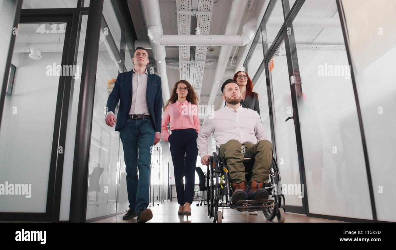 Eine erfolgreiche Geschäft Leute gehen durch den Flur in das Office Center. Ein Mann im Rollstuhl Stockfoto