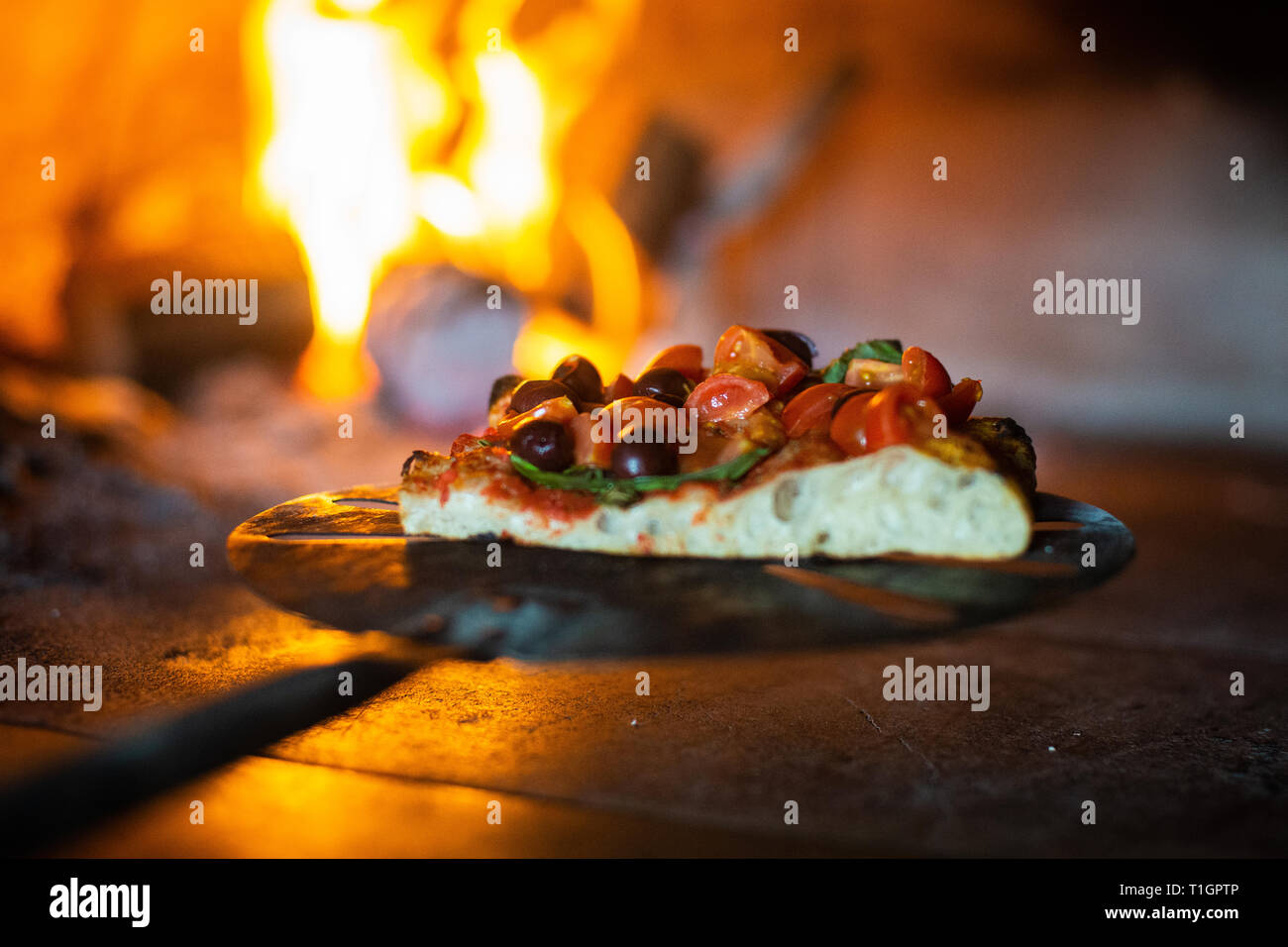 Eine Scheibe des authentischen italienischen Holzofen Pizza in Ofen in eine Pizzeria/Trattoria. Selektiver Fokus Stockfoto