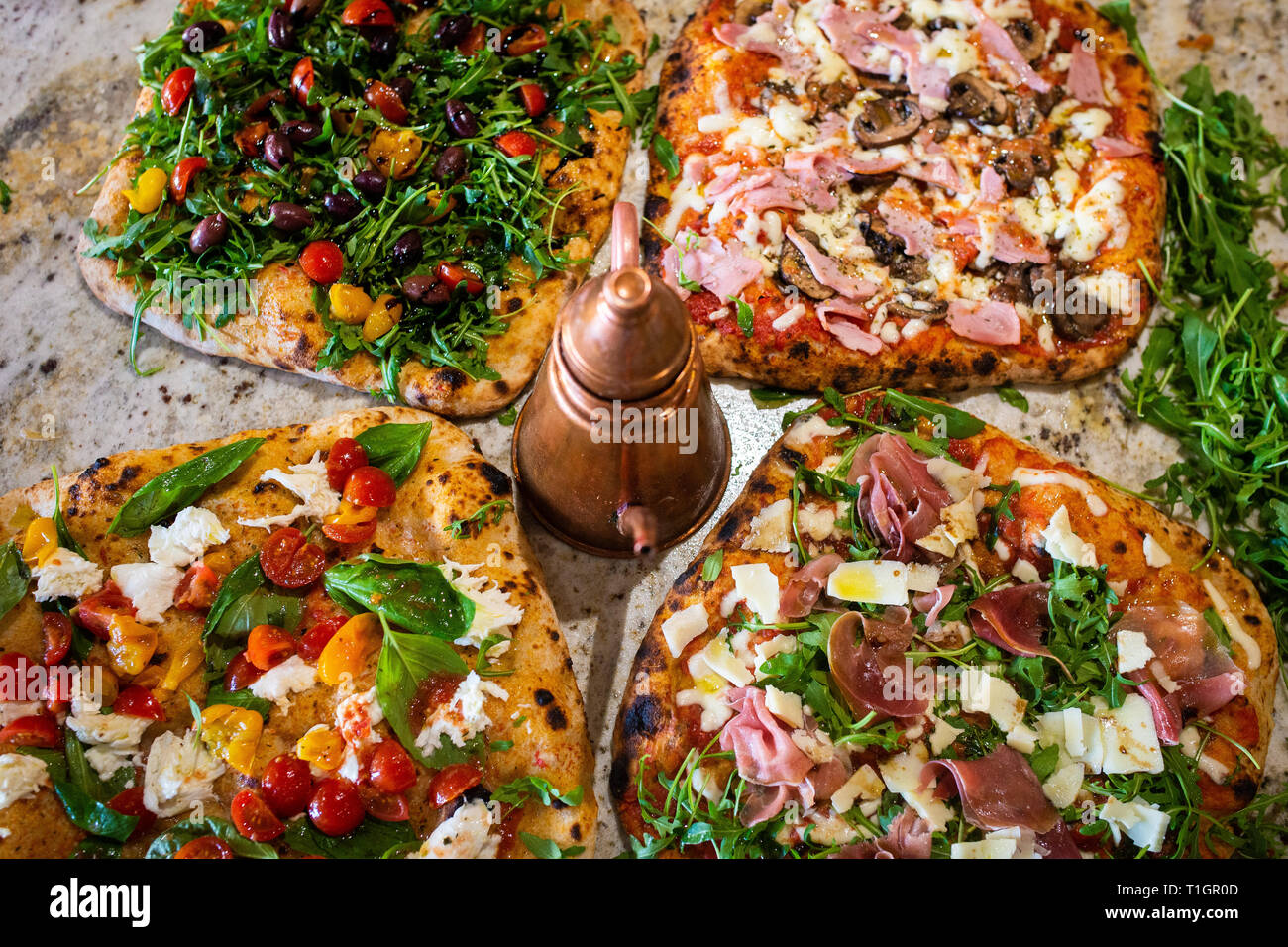 Eine Auswahl an authentischen Römisch-italienischen Stil Holzofen Pizzas, auf einem Marmor Zähler, in einer Trattoria Pizzeria Restaurant Stockfoto