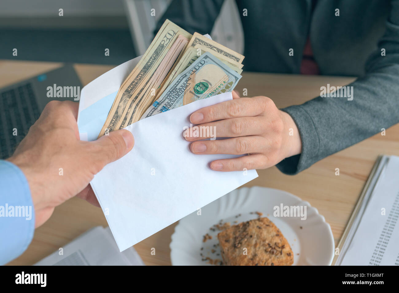 Business Schmiergeld und Korruption, Mann mit Bargeld in US-Dollar Papier Währung in einem Briefumschlag an weiblichen Geschäft Person Stockfoto