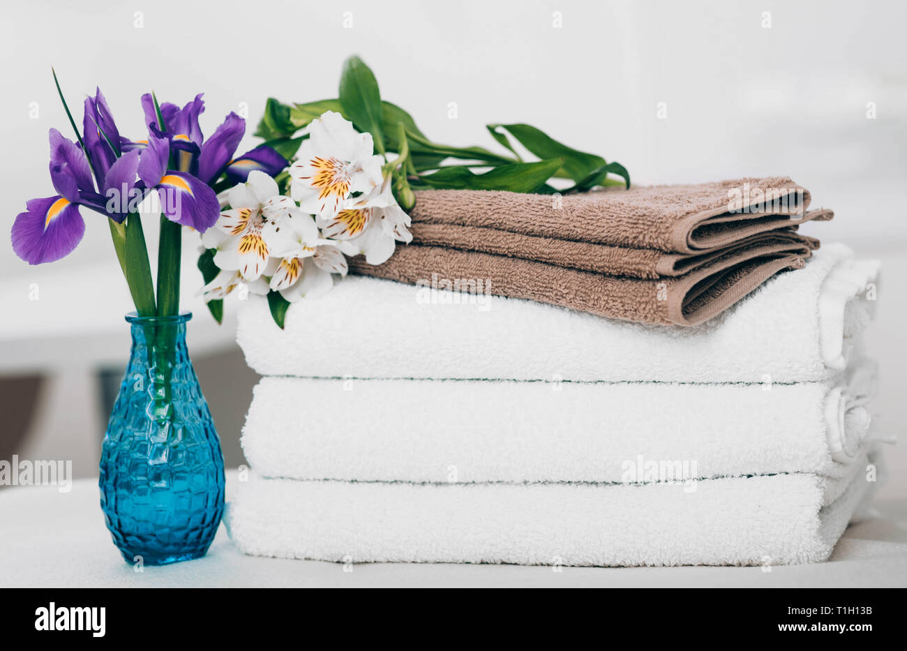 Ruhige Szene mit Handtüchern und Blumen im Spa. Weiße Handtücher, Aromatherapie und Wellness Behandlung Stockfoto