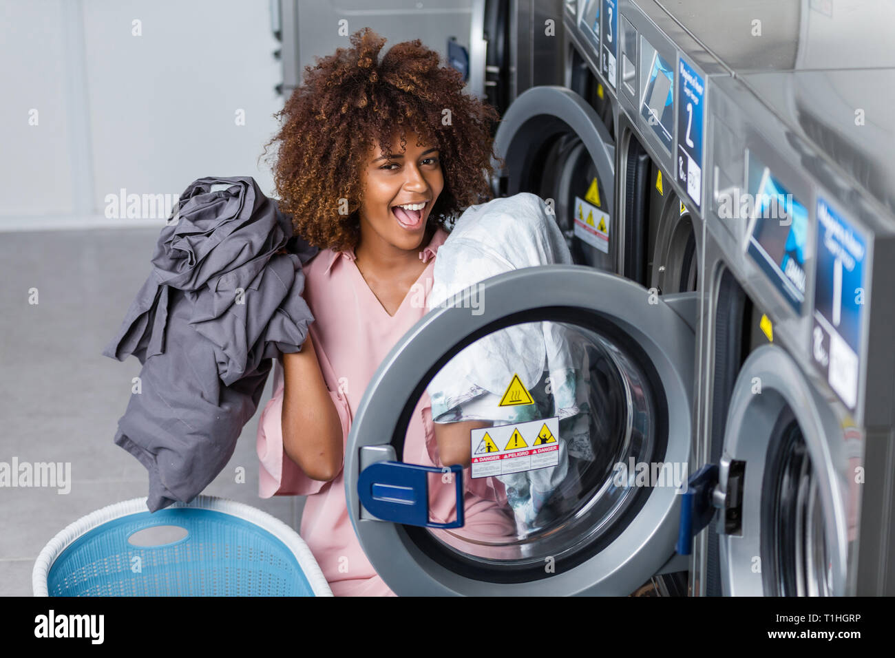 Junge schwarze afrikanische amerikanische Frau, die ihre Kleider waschen in einem Waschsalon Stockfoto