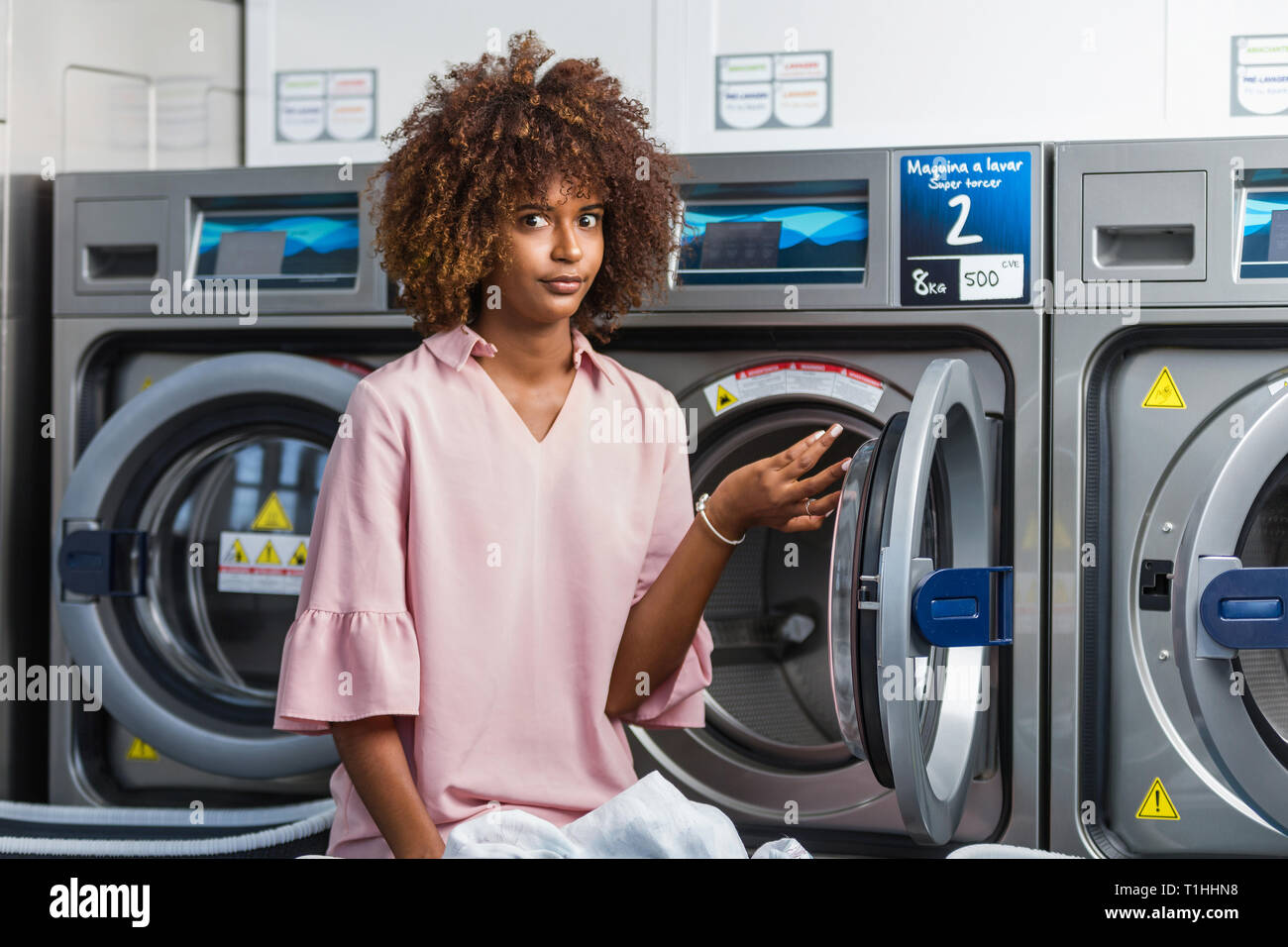 Junge schwarze afrikanische amerikanische Frau, die ihre Kleider waschen in einem Waschsalon Stockfoto