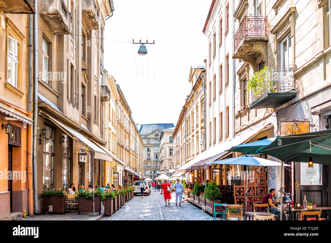Lemberg, Ukraine - August 1, 2018: Street im historischen Ukrainischen Lvov Stadt bei Tag mit gelben alten Vintage Gebäude in der Altstadt und Cafe Tische Stühle Stockfoto