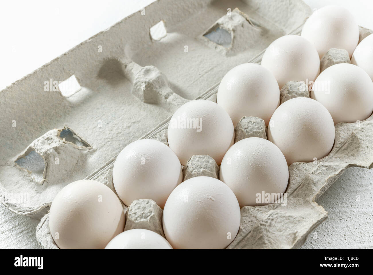 Frische weiße Eier im Karton auf Weiß, Nahaufnahme Stockfoto