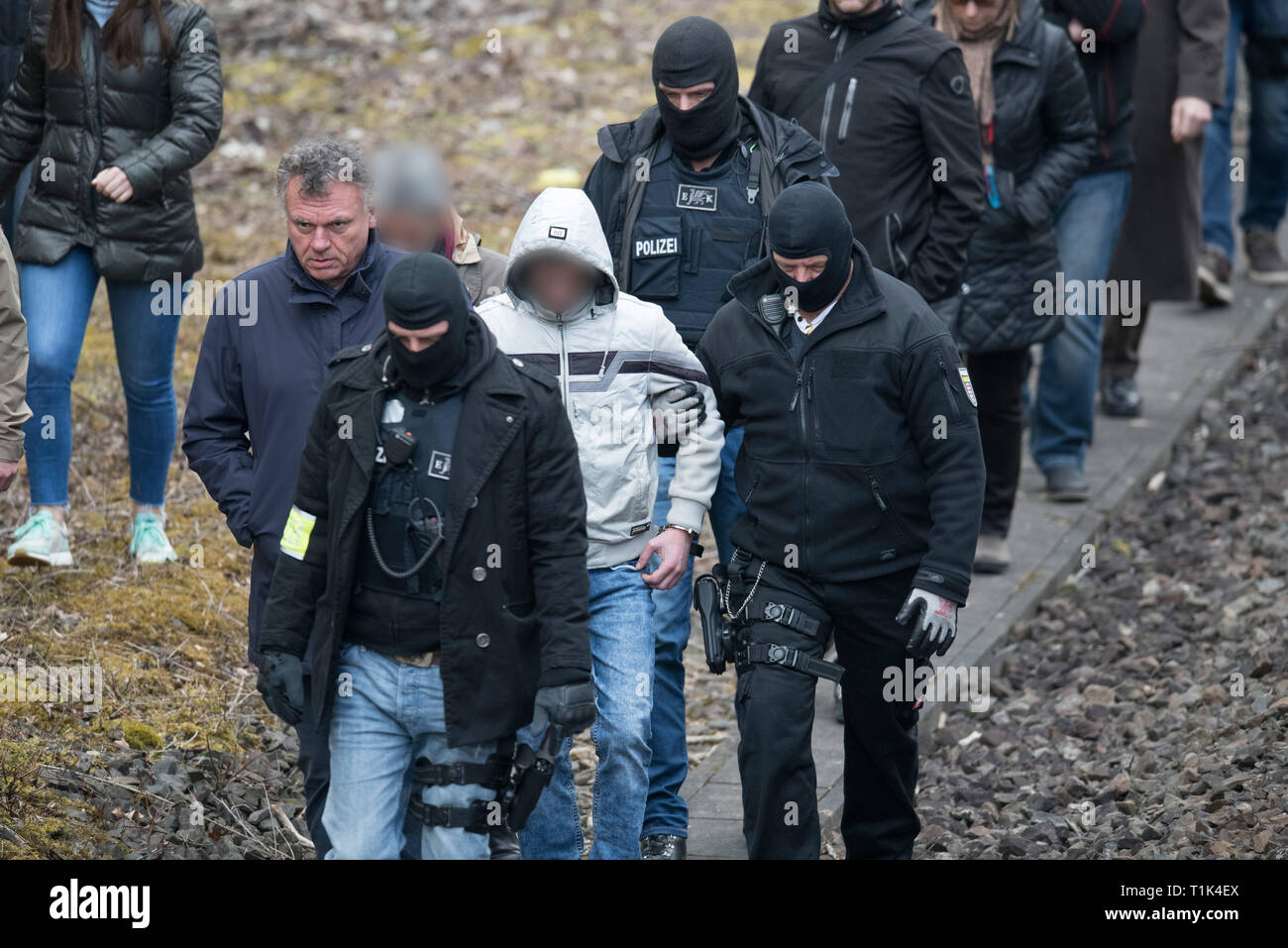 Wiesbaden, Deutschland. 27 Mär, 2019. Von maskierten Polizisten begleitet, Ali B., warf der Ermordung der 14-jährige Susanna, ist entlang einer Bahnstrecke in der Nähe von Erbenheim geführt. Zu seiner Linken ist sein Rechtsanwalt. Hier der Mann, der aus dem Irak stammen, angeblich das Mädchen vergewaltigt und dann getötet und begraben ihren Körper. Credit: Boris Roessler/dpa/Alamy leben Nachrichten Stockfoto