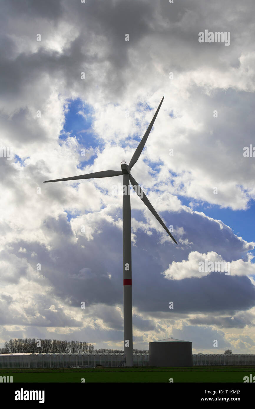 Eine Windmühle durch dramatische Wolken, die den blauen Himmel verstecken umgeben Stockfoto