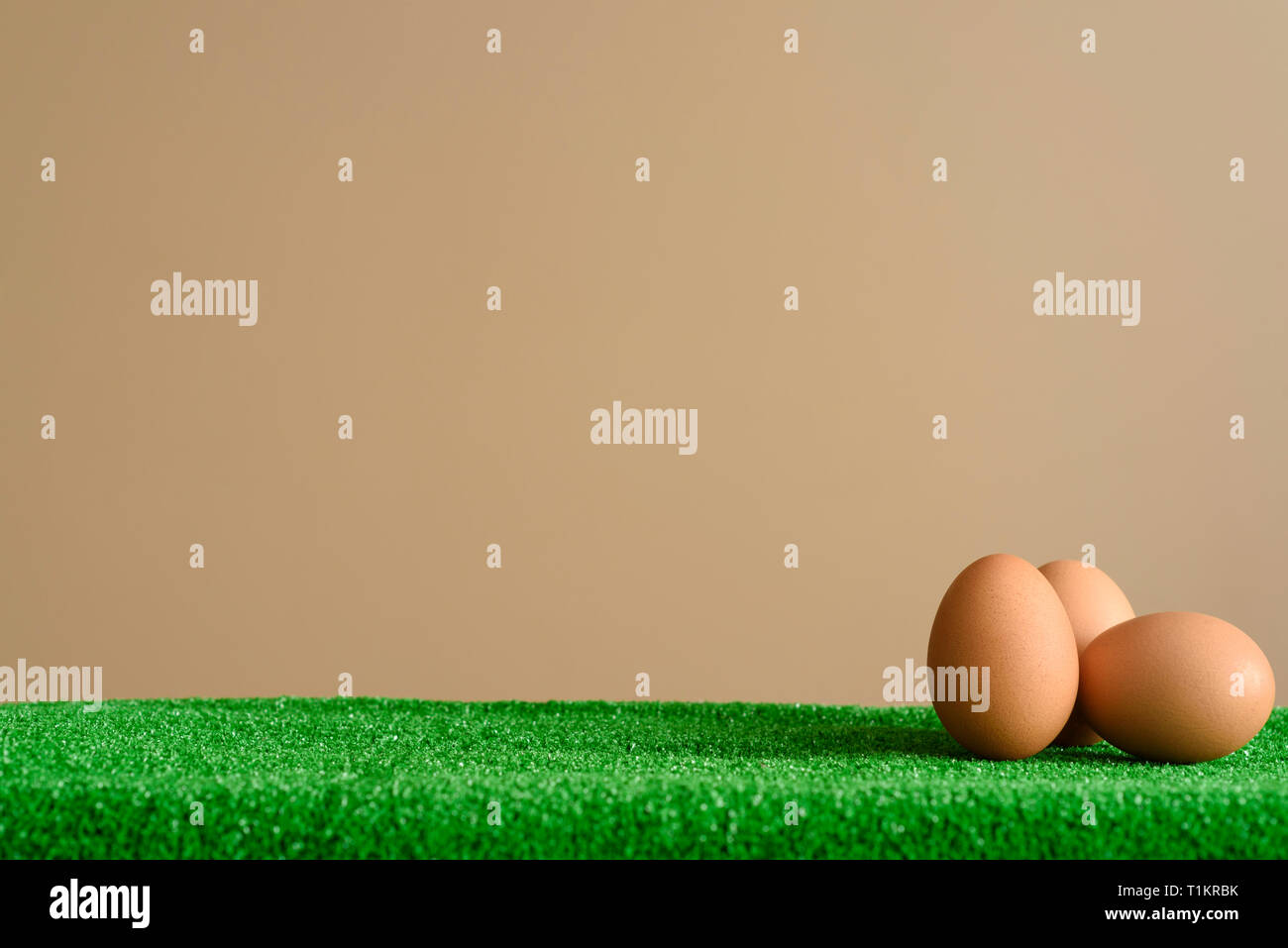 Gruppe von Eiern in einer Ecke lag, auf grünem Gras. Kopieren Sie Speicherplatz auf einem braunen Hintergrund. Osterferien Konzept. Stockfoto