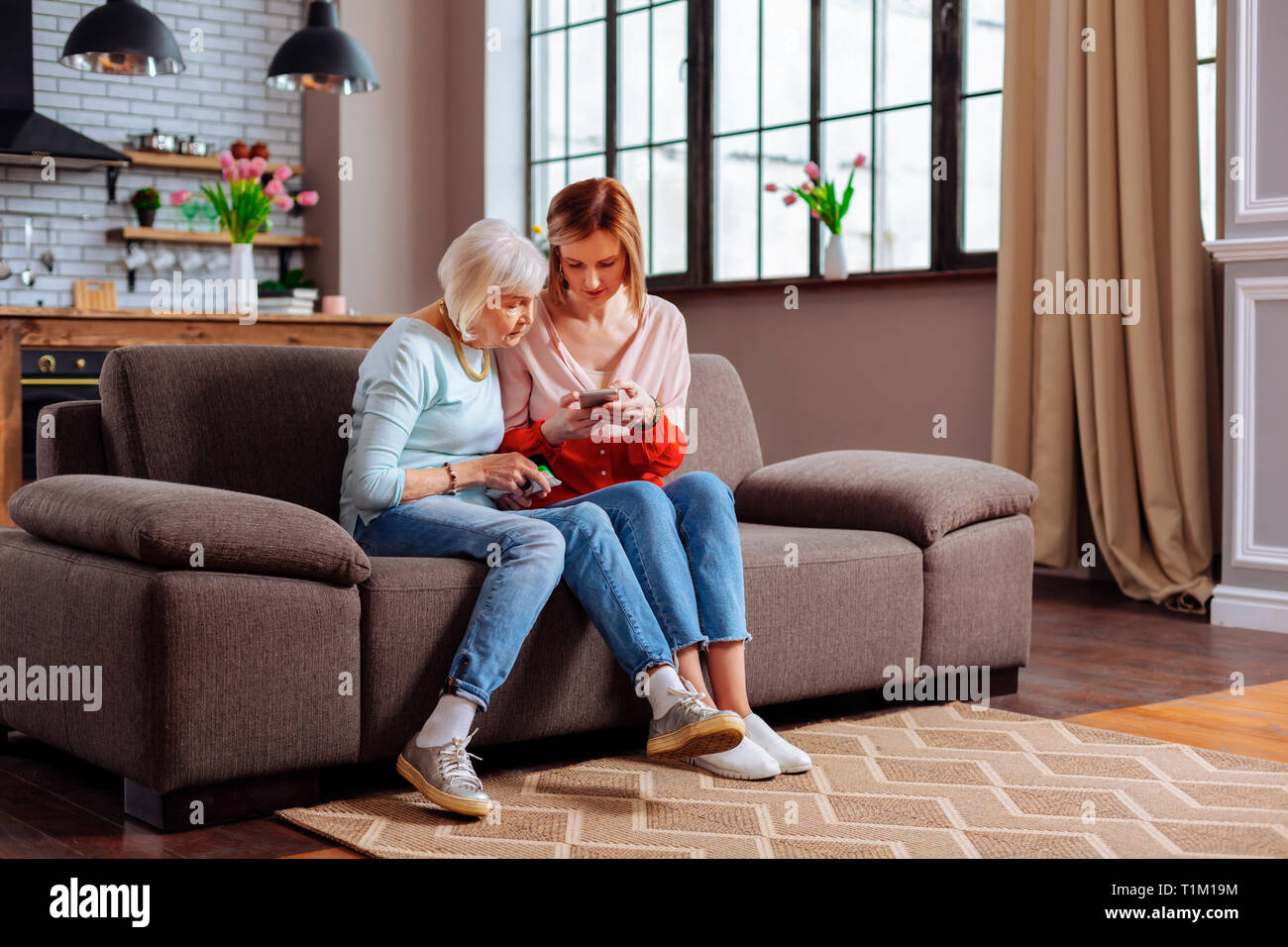 Ältere Frauen sitzen auf einem Sofa mit ihrer Jungen - erwachsene Tochter Stockfoto