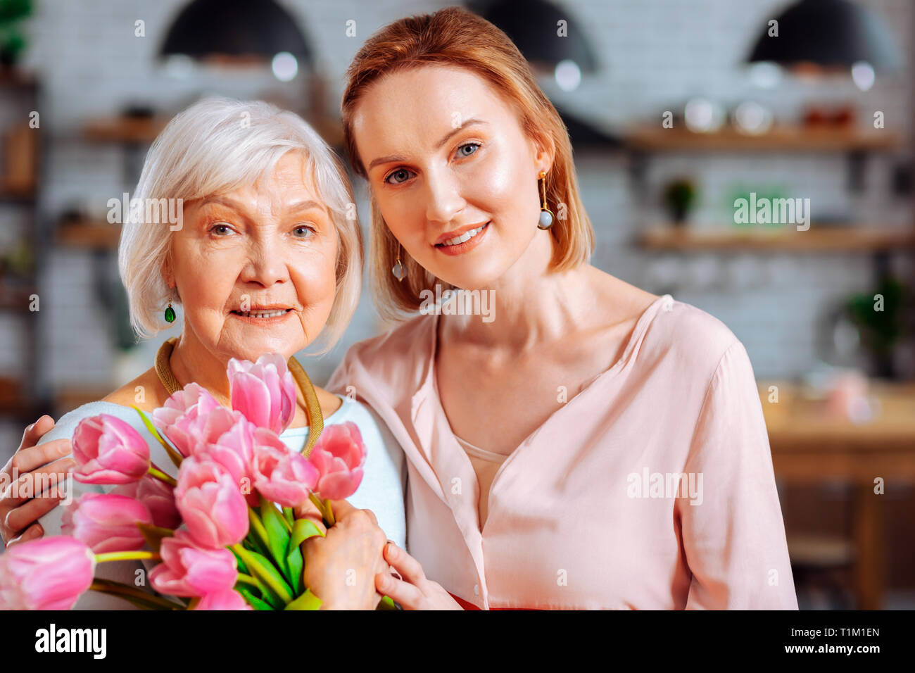 Attraktive lady Kuscheln im Alter von Mama mit Bündel Tulpen Stockfoto