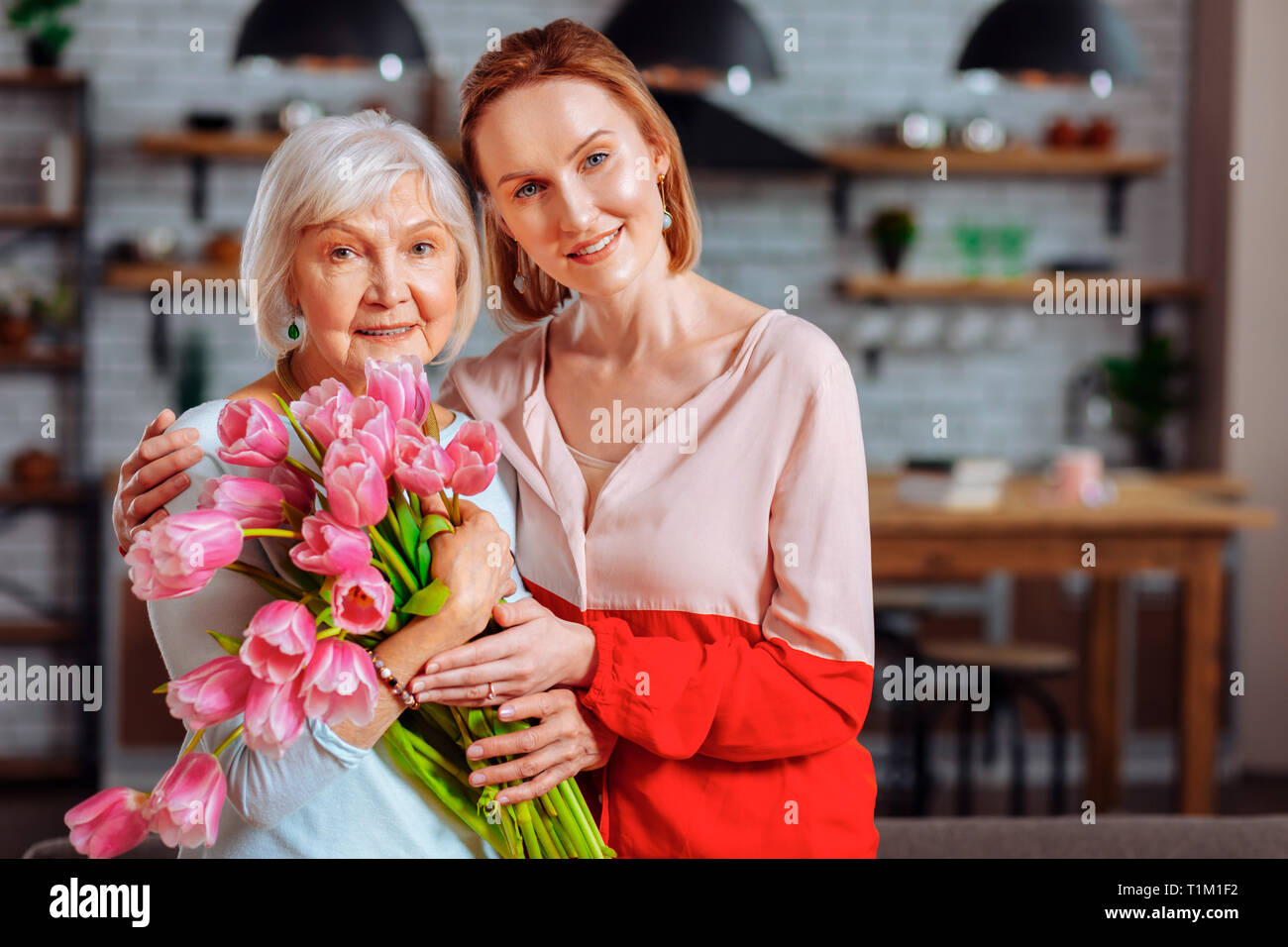 Attraktive Tochter mit Silber posing blonde Mutter mit Tulpen Blumenstrauß Stockfoto