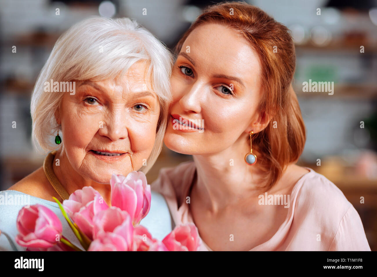 Portrait Foto der reifen Tochter umarmen grauhaarige Mutter Tulpen Holding Stockfoto