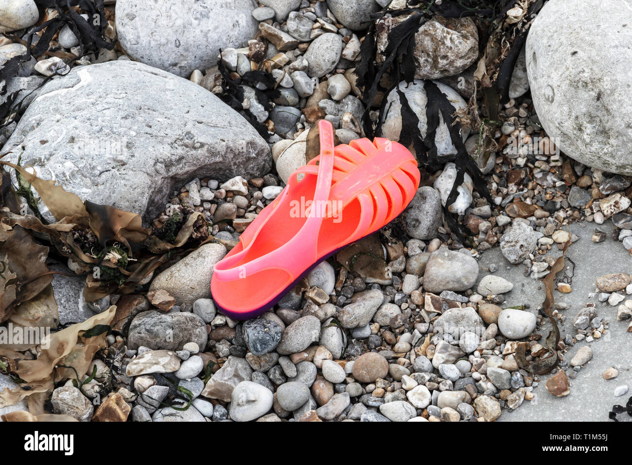 Ein helles Rosa Plastik jelly Schuh verlassen auf einem steinigen Strand verloren geht oder Stockfoto Ein helles Rosa Plastik jelly Schuh verlassen auf einem steinigen Strand verloren geht oder Stockfoto