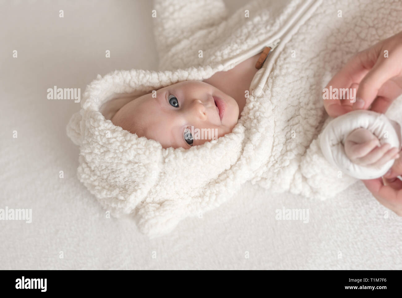Schöne Mädchen in einem warmen weissen Anzug liegen auf einem Bett. Stockfoto