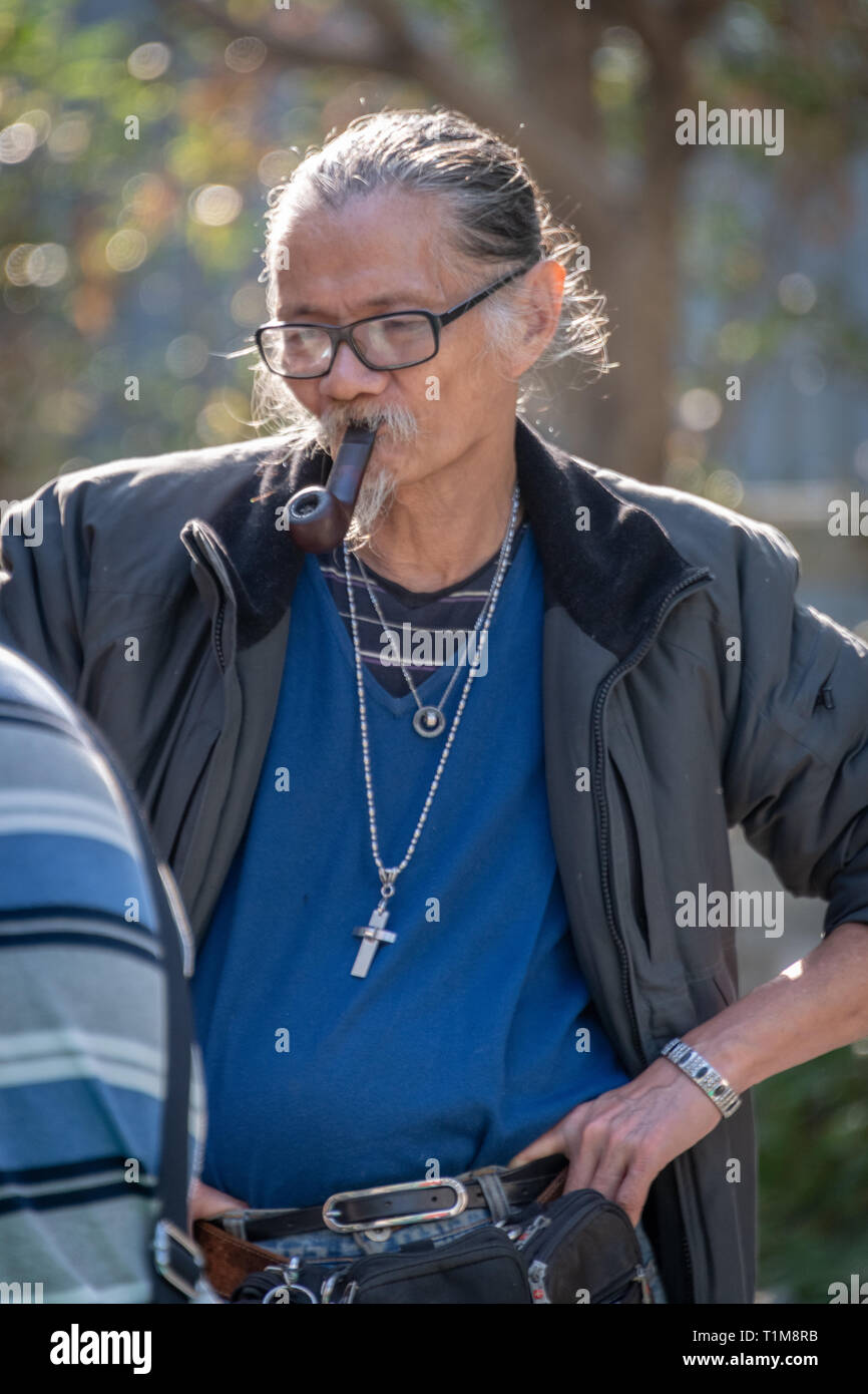 Chinesischer Mann rauchen Rohr in Park Stockfoto