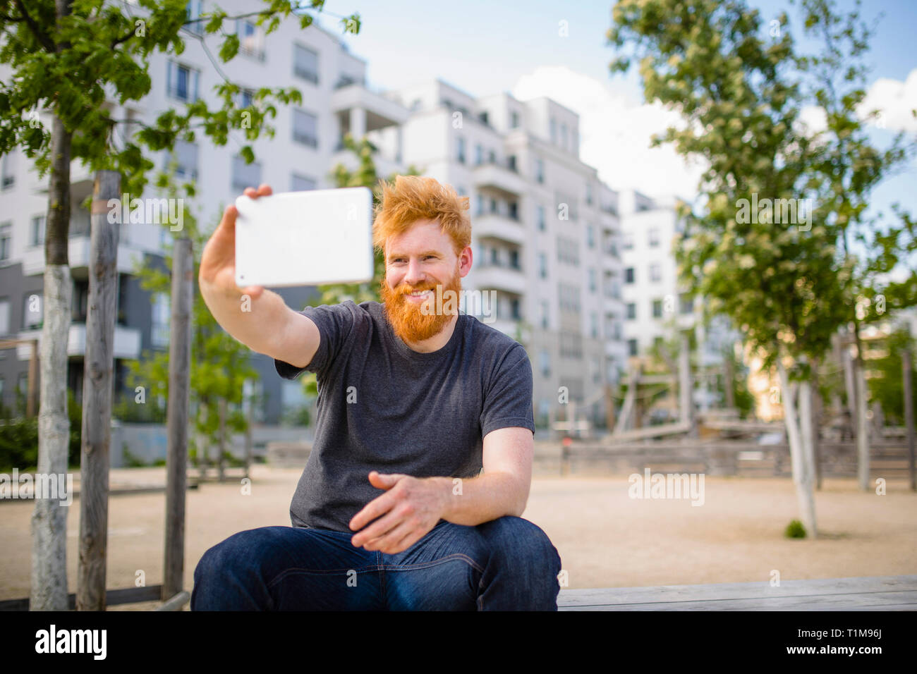 Lächelnder Mann mit Bart nimmt Selfie mit digitalem Tablet in der Stadt auf Stockfoto