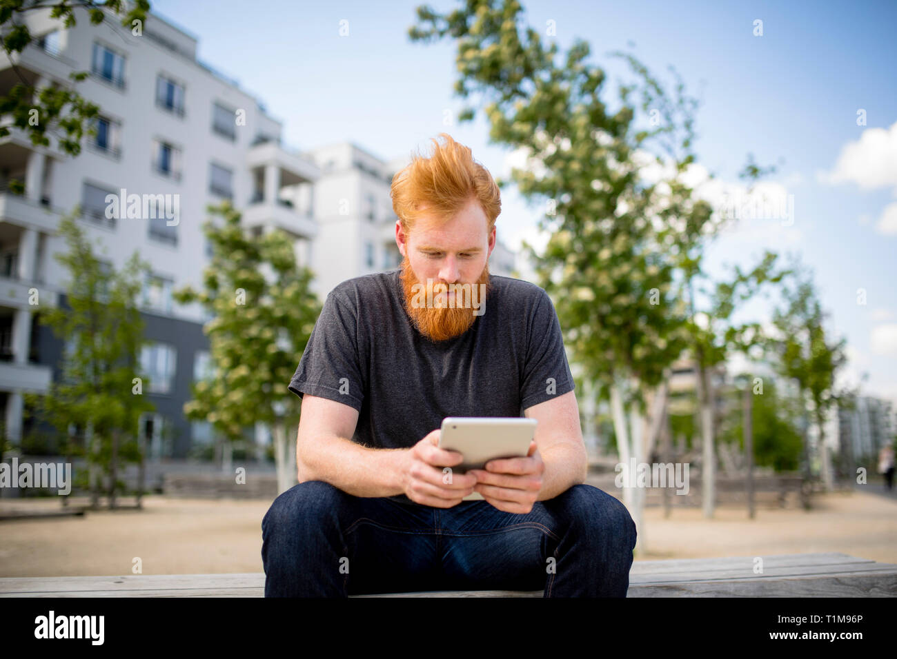 Mann mit Bart mit digitalem Tablet auf der städtischen Bank Stockfoto
