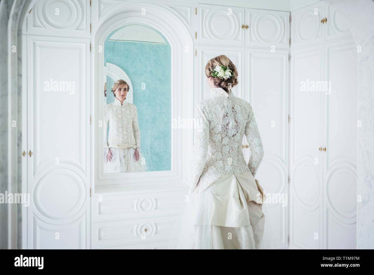 Elegante Braut in Lace wedding dress bei Spiegel Stockfoto