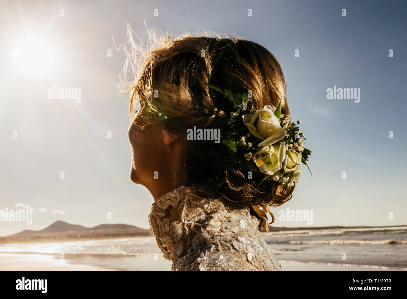 Braut mit Blumen im Haar am sonnigen Meeresstrand Stockfoto