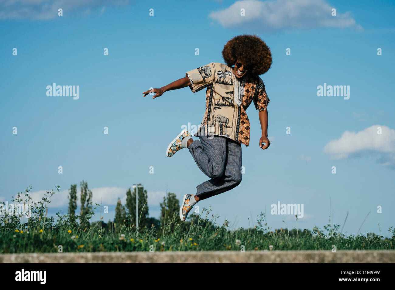 Sorgloser junger Mann mit Afro vor Freude hüpfend Stockfoto