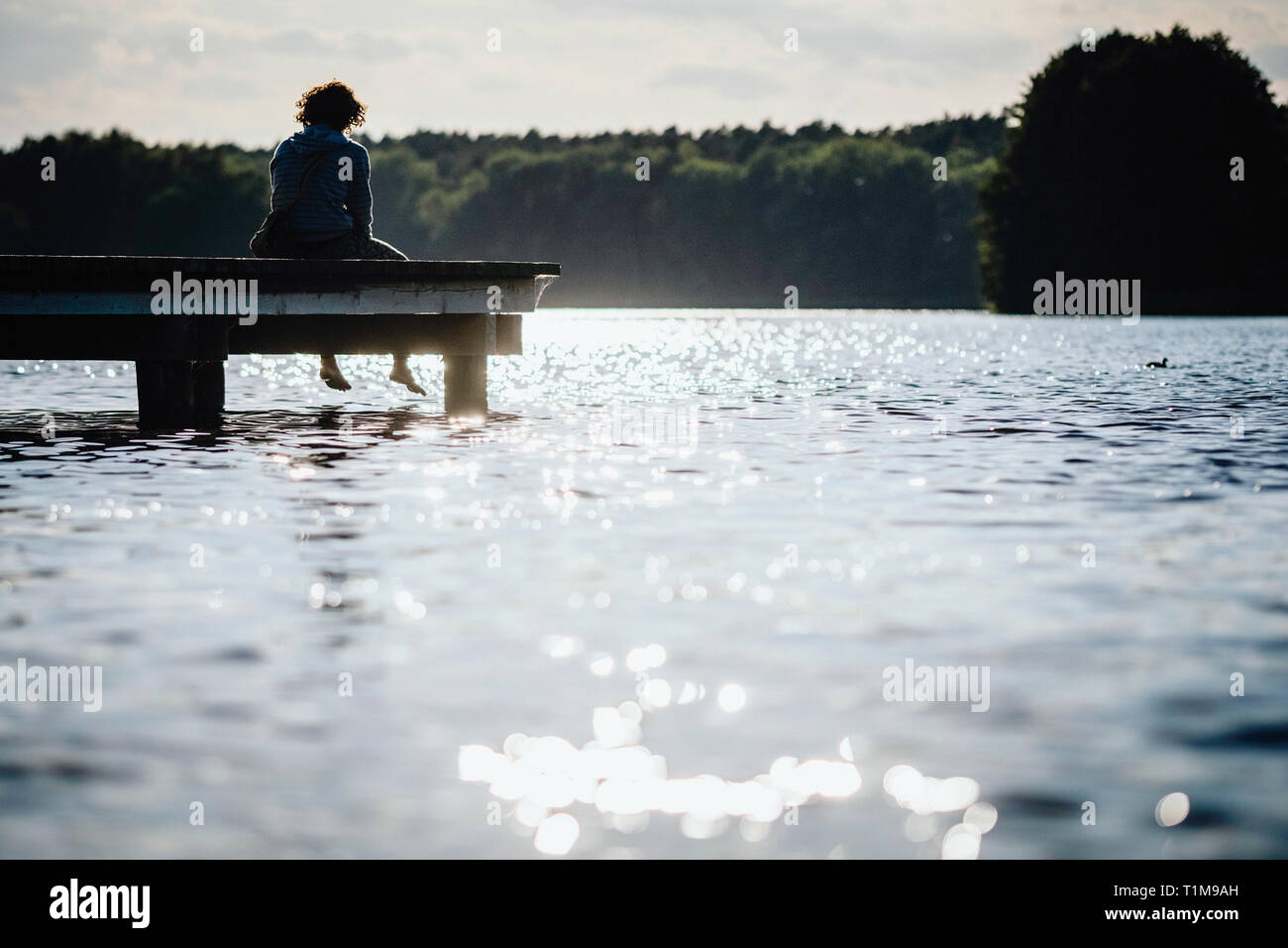 Frau entspannend am Rande der sonnigen See dock Stockfoto
