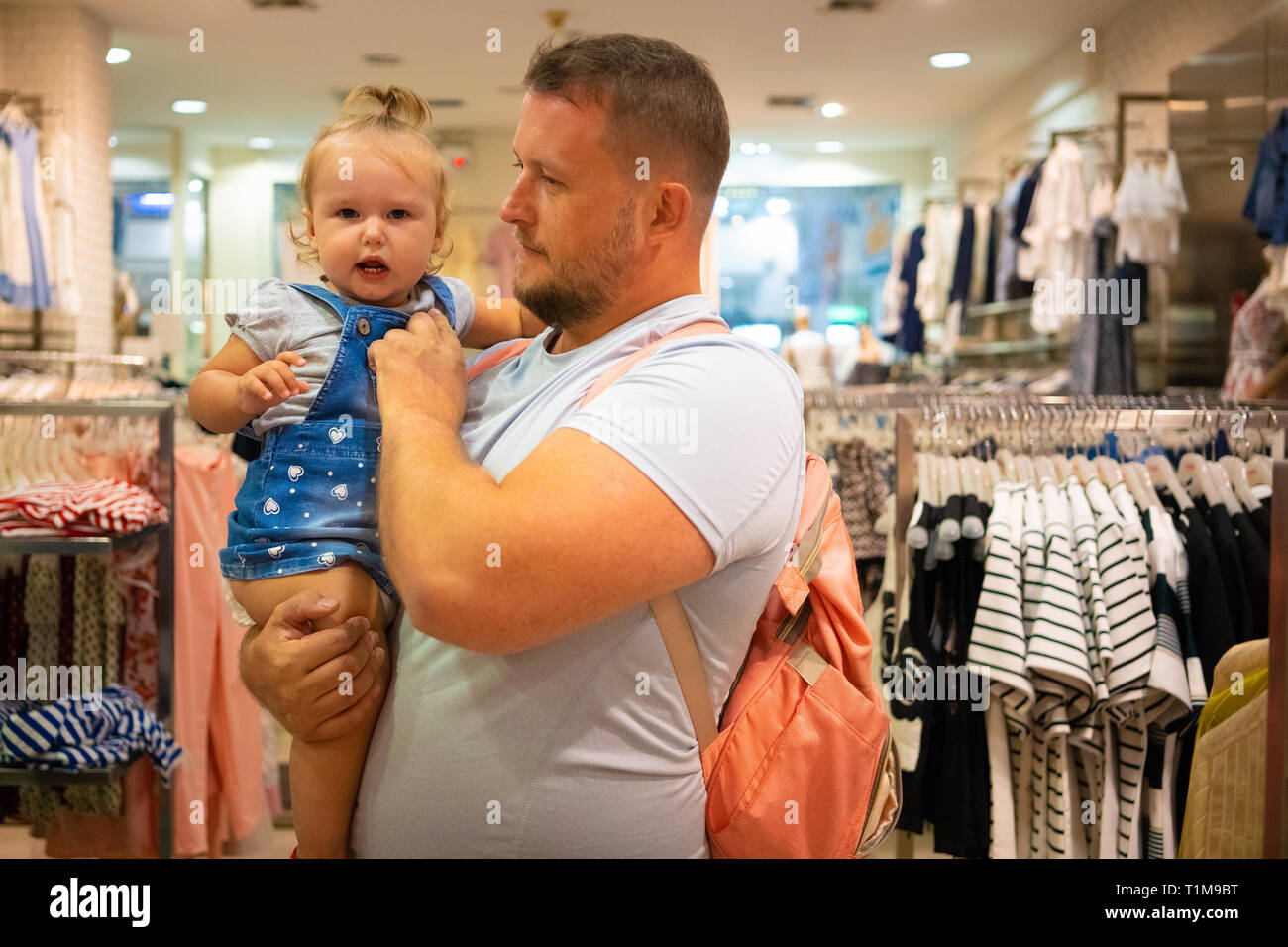 Vati mit Kind Mädchen wählt und kauft Kleidung im Store, Konzept der Vaterschaft. Stockfoto