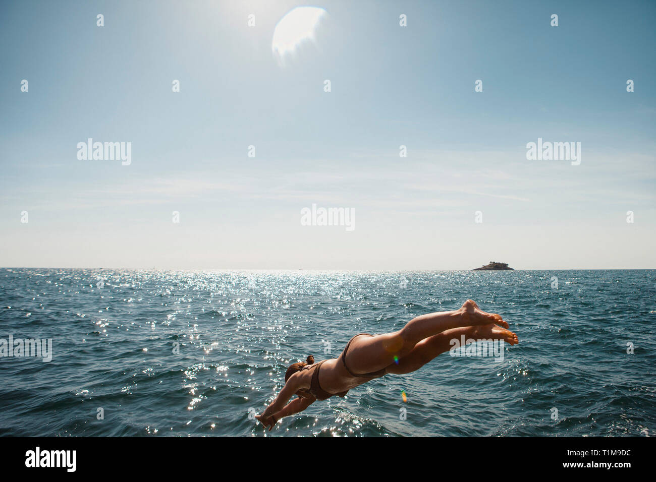 Frau, die in den sonnigen blauen Ozean taucht, Rovinj, Kroatien Stockfoto